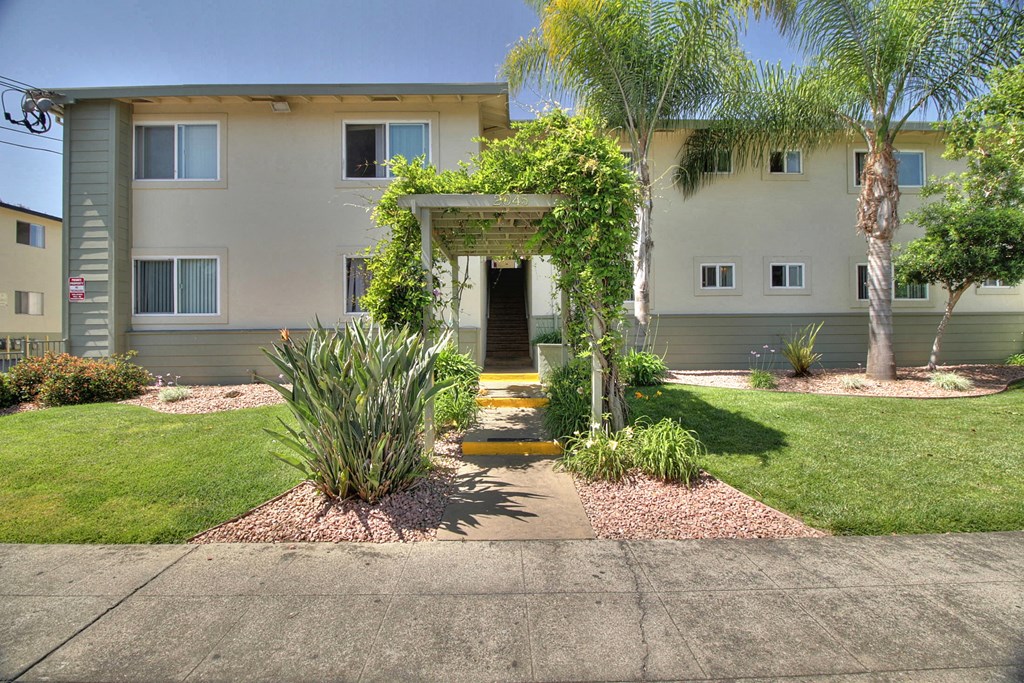 the front of the building with a walkway and plants