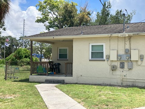 A house with a white exterior and a brown roof with a small porch and a white door.