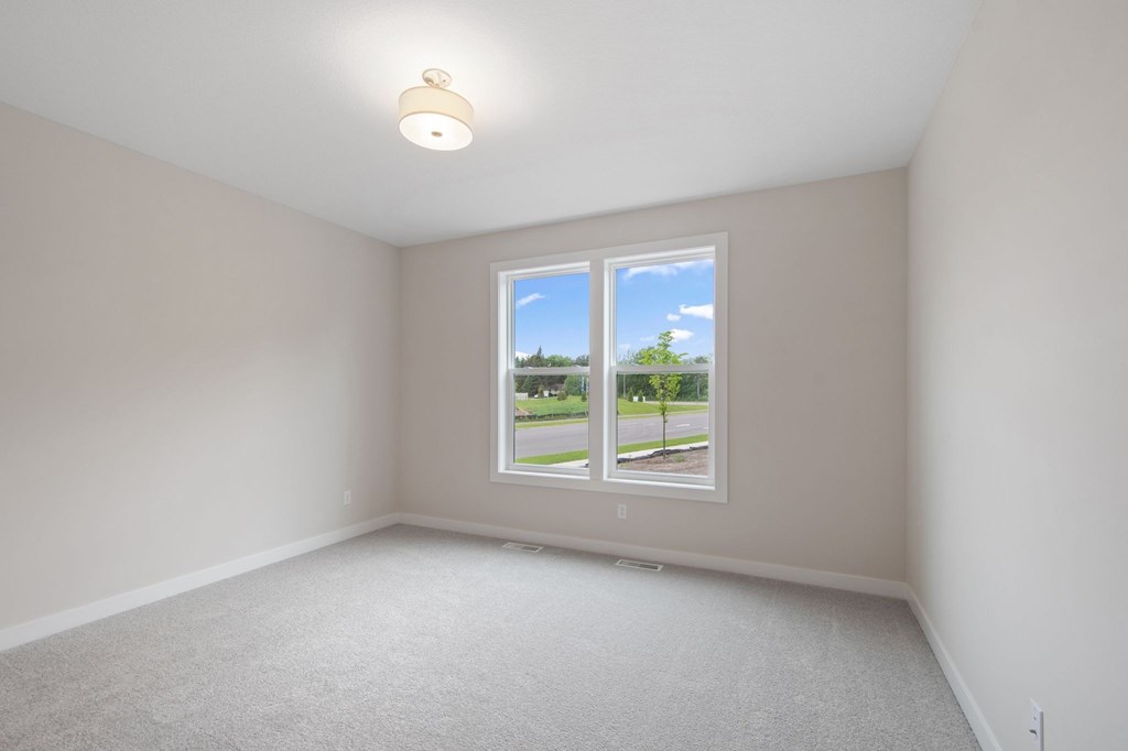 A room with a window showing a view of a street and houses.