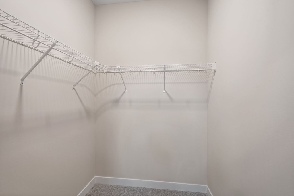 Empty white closet with clothes hangers.