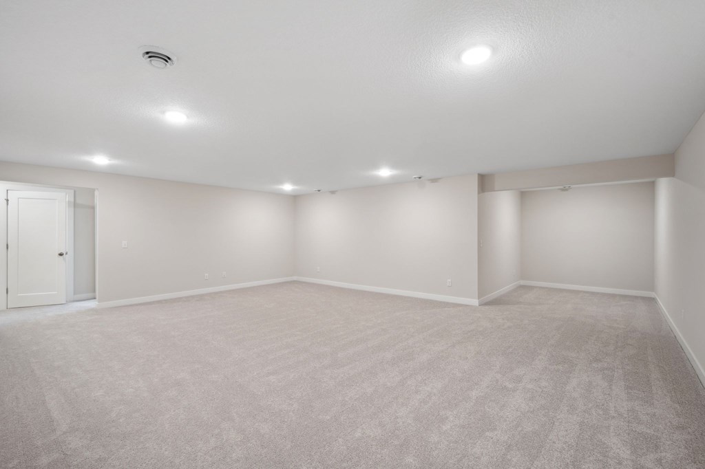 A large empty room with carpeted floor and white walls.