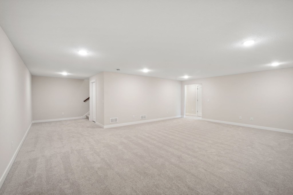 A large, empty room with carpeted flooring and white walls.