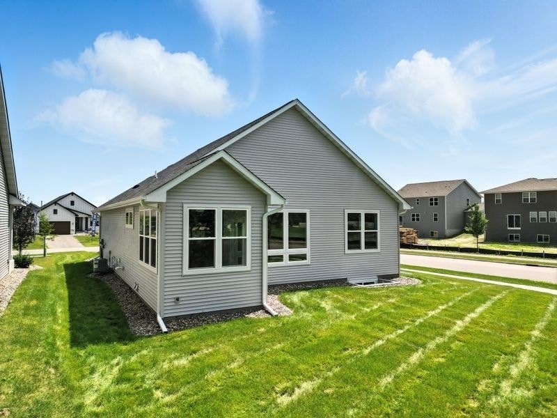A house with a grey roof and white windows is surrounded by a green lawn.