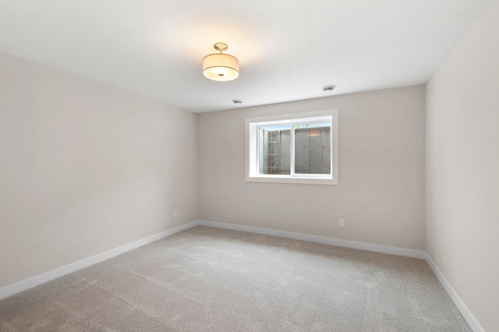 A room with a carpeted floor and a window with blinds.