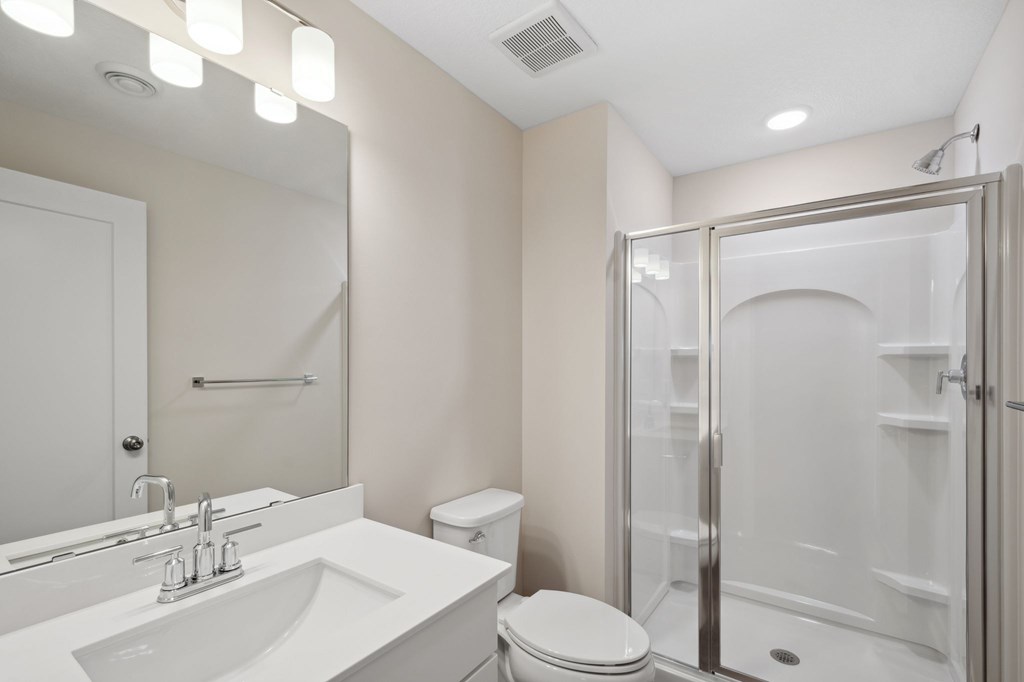 A white bathroom with a sink, toilet, and shower.