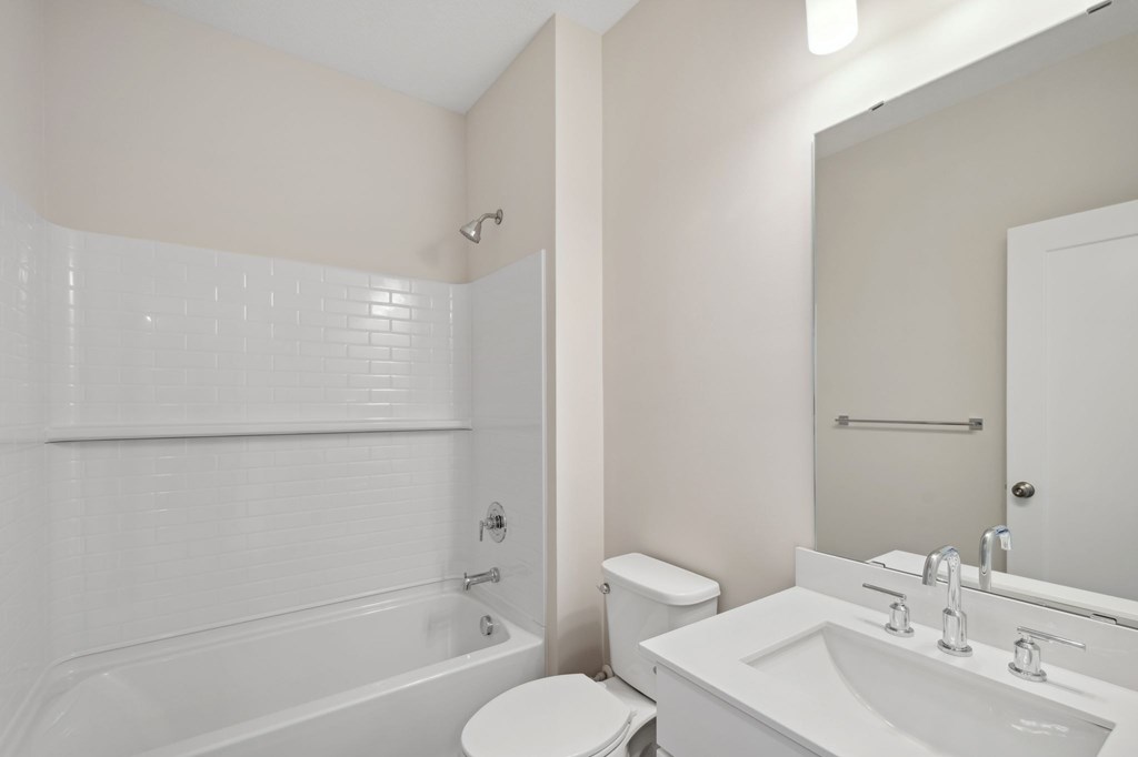 A white bathroom with a toilet, sink, and bathtub.