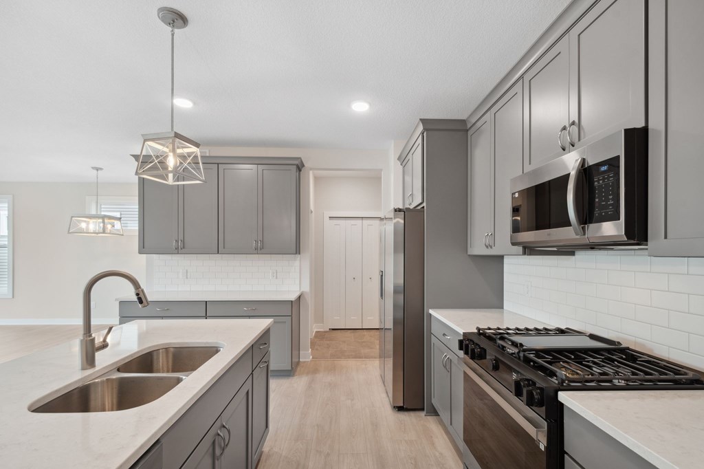 A modern kitchen with a stainless steel sink and a black stove top oven.