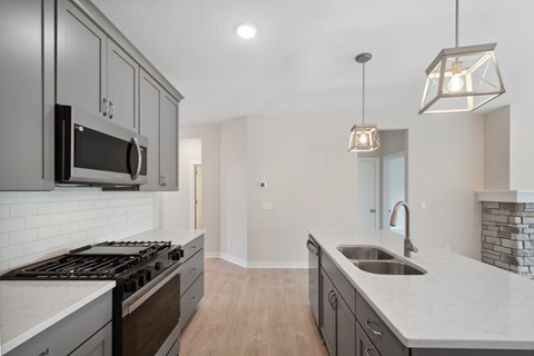 A modern kitchen with a stove top oven and a microwave above it.