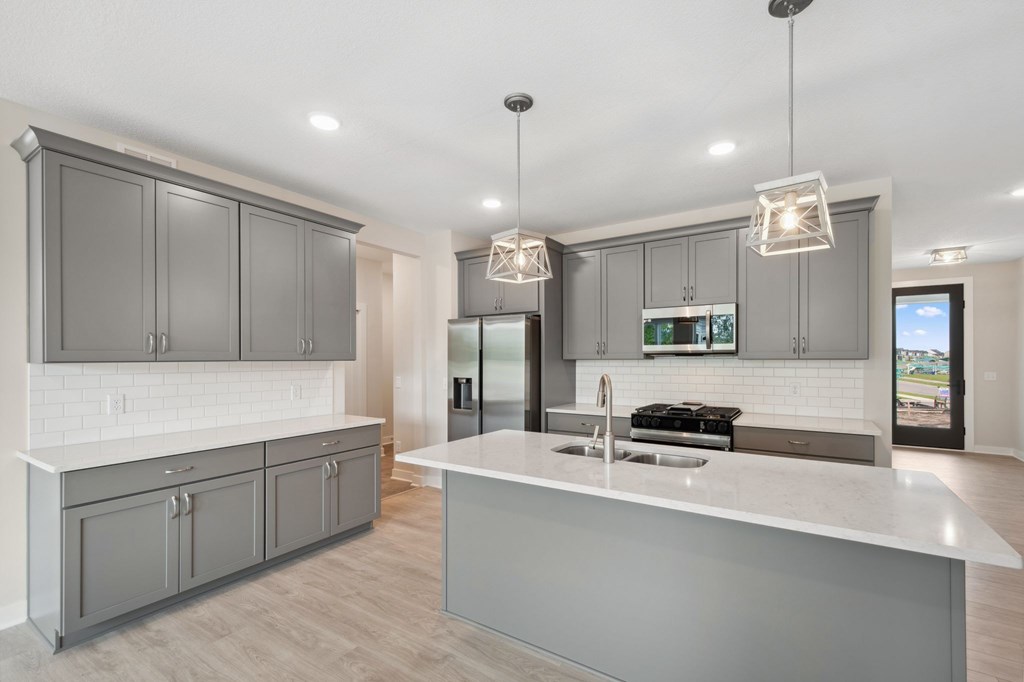 A modern kitchen with a large island and grey cabinets.