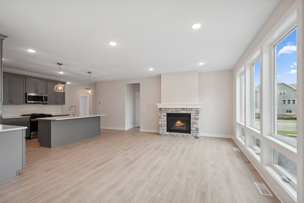A spacious living room with a fireplace and a kitchen area.