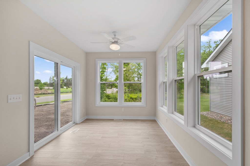 A room with a ceiling fan and sliding glass doors.