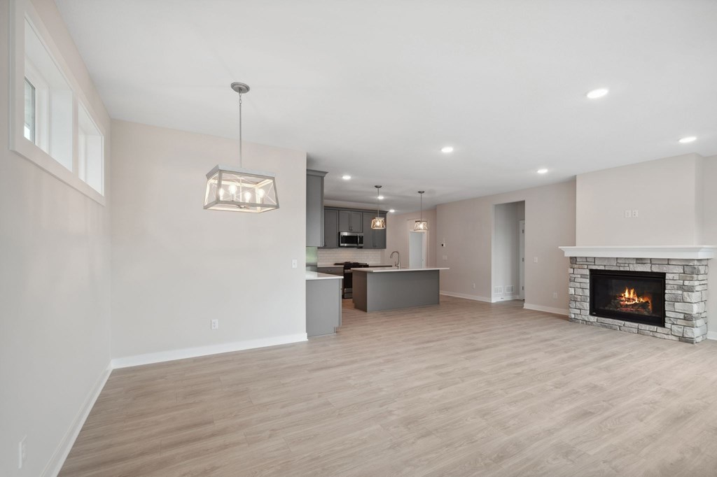 A modern living room with a fireplace and a kitchen area in the background.