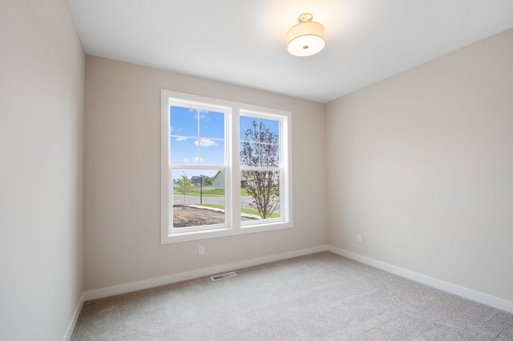 A room with a window showing a view of a house and trees.