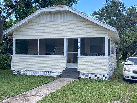 A small white house with a car parked in front.