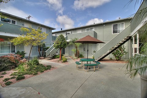 a patio with a table and chairs in front of a building