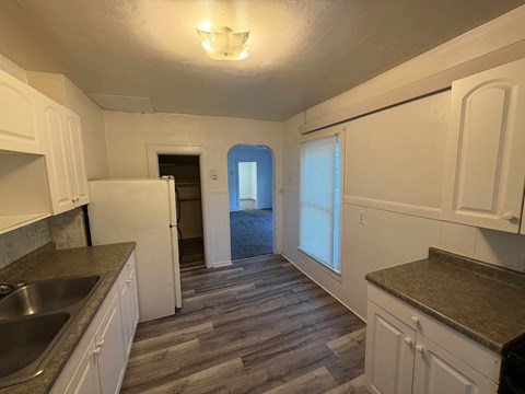 A kitchen with white cabinets and a wooden floor.