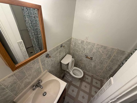 A bathroom with a toilet, sink, and mirror.