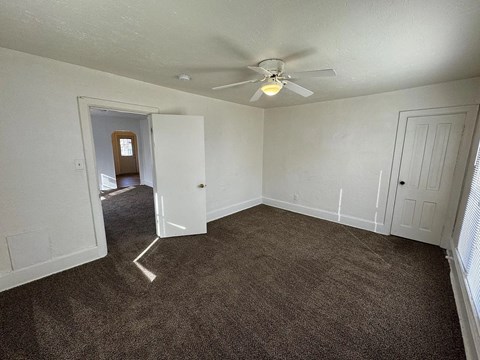 A room with a ceiling fan and carpeted floor.