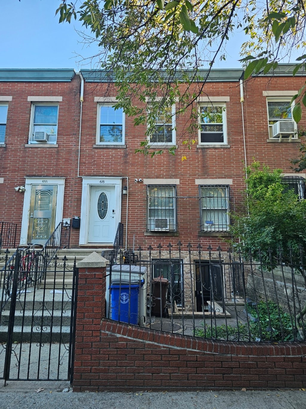 A red brick building with a blue trash can in front.