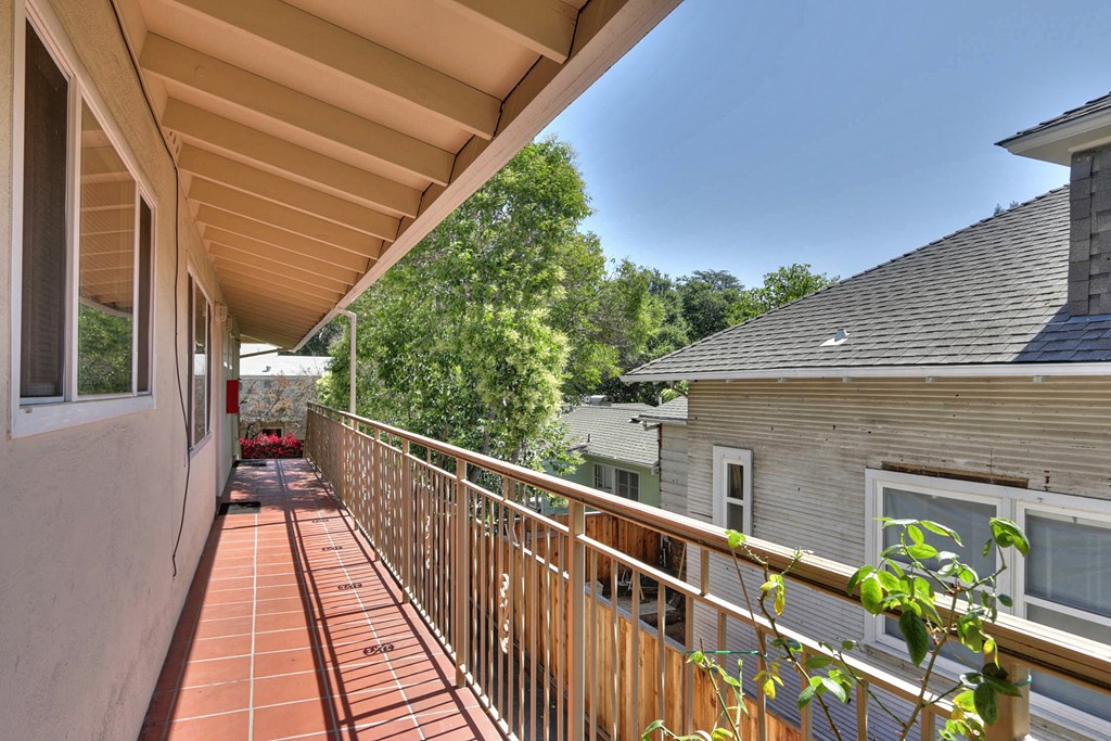 a balcony with a wooden railing and a house in the background
