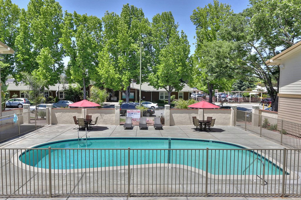 A pool surrounded by a fence with trees in the background.