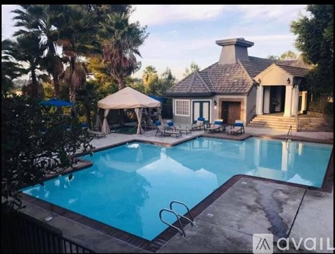 A pool with a house and a canopy in the background.