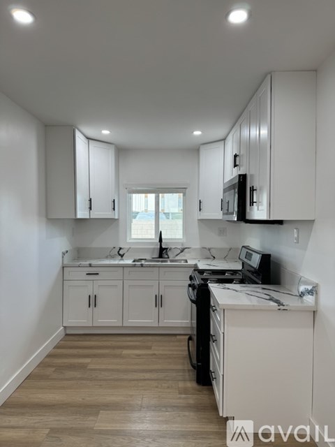 A kitchen with white cabinets and a wooden floor.