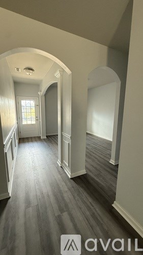 A hallway with a wooden floor and white walls.