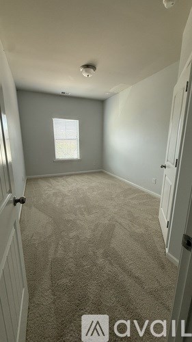 A room with a carpeted floor and a window with blinds.