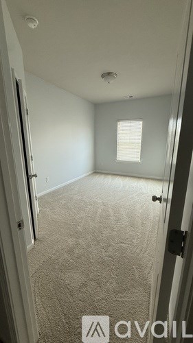 A room with a carpeted floor and a window with blinds.