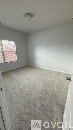 A room with a carpeted floor and a window with blinds.