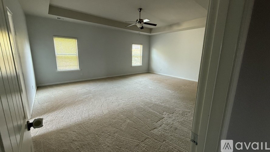 A room with a carpeted floor and a ceiling fan.