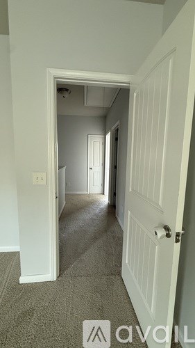 A hallway with a carpeted floor and white walls.