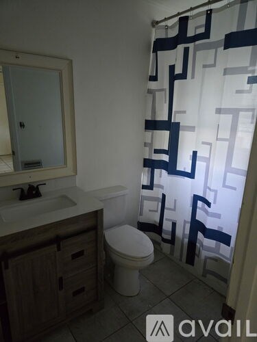 A bathroom with a toilet, sink, and shower curtain.