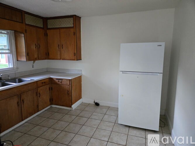 A kitchen with a white fridge and wooden cabinets.