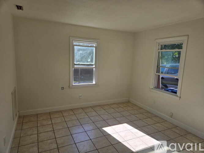 A room with two windows and tiled flooring.