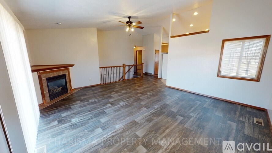 A spacious living room with a fireplace and a ceiling fan.