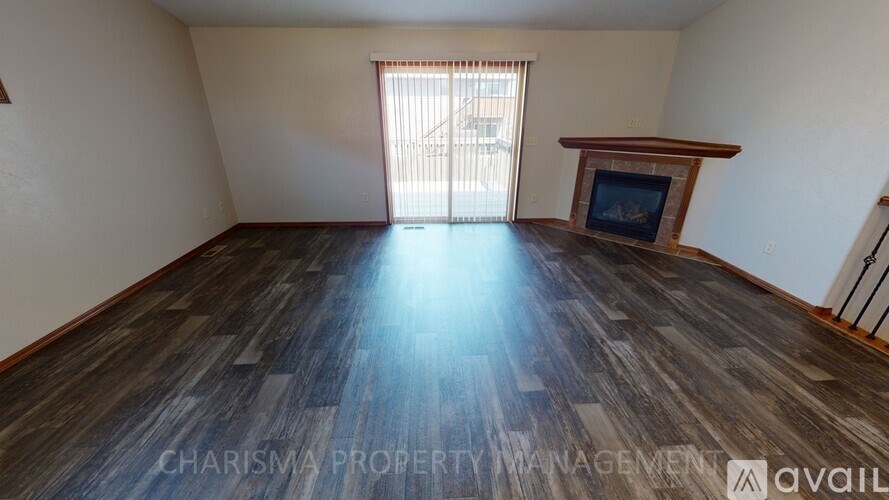 A spacious living room with wood flooring and a fireplace.
