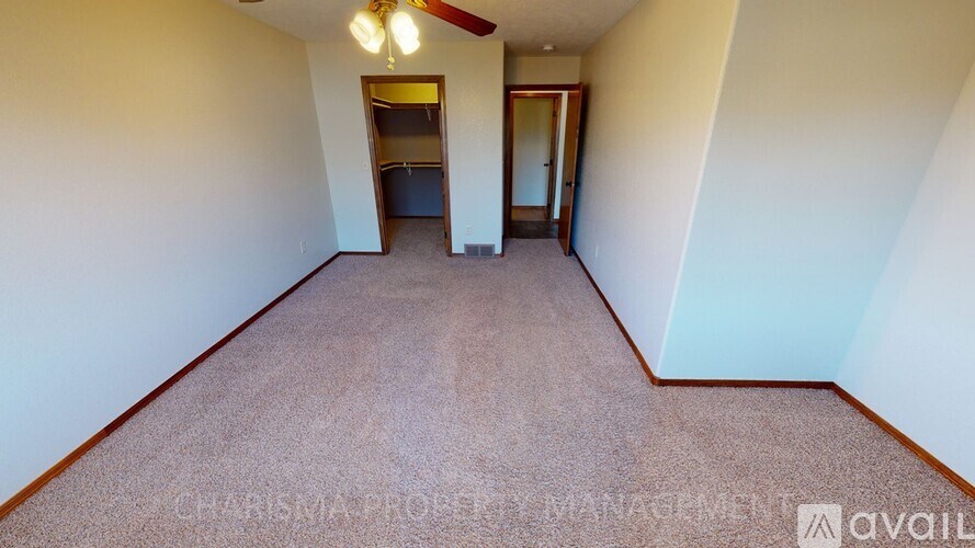 A spacious room with a carpeted floor and a ceiling fan.