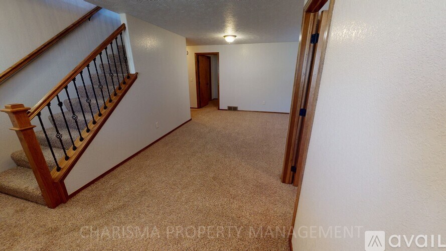 A spacious room with a staircase and carpeted floor.