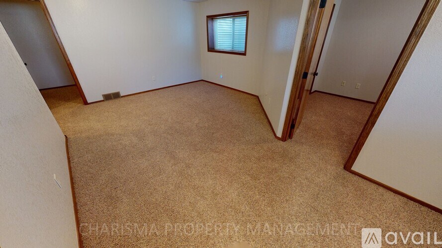 A carpeted room with a door and a window.