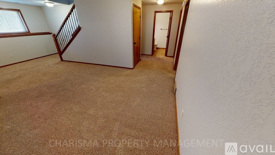 A carpeted room with a staircase leading to another room.