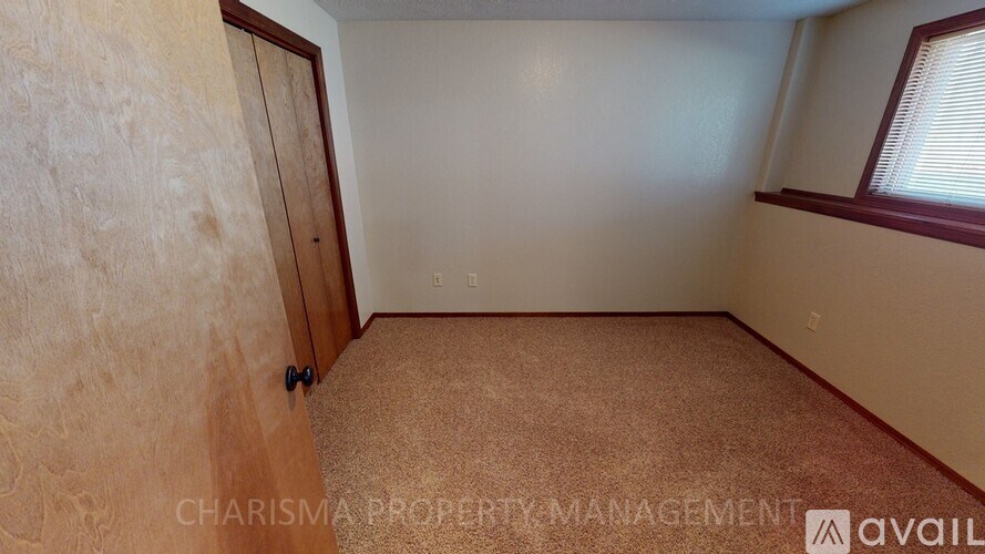 A room with a carpeted floor and a wooden door.