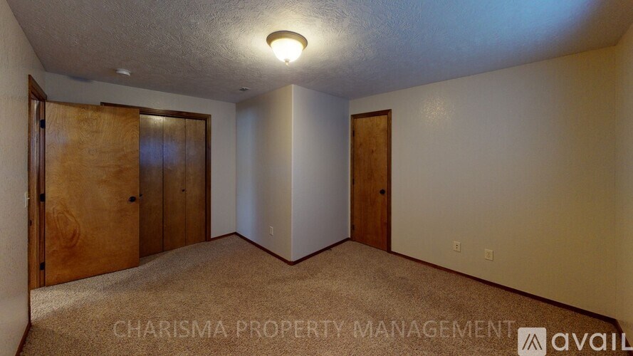 A room with carpeted floor and two wooden doors.