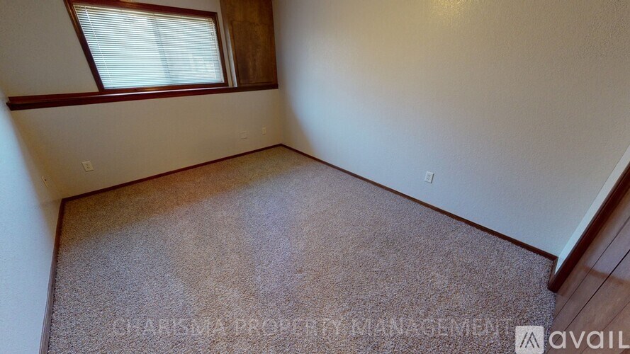A room with a carpeted floor and a window with blinds.