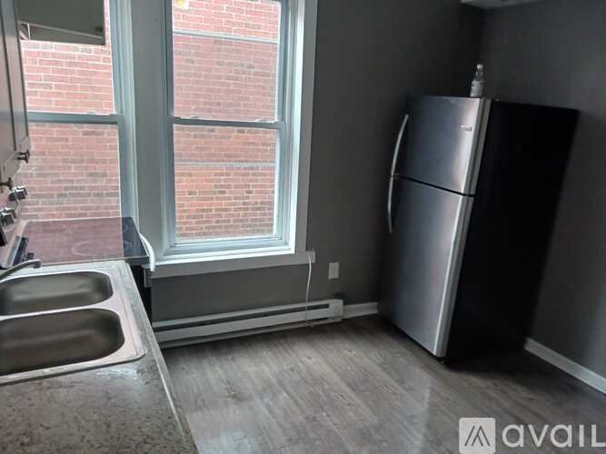 A kitchen with a window, sink, and refrigerator.