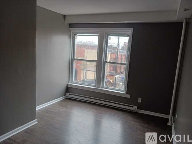 A room with a large window and wooden flooring.