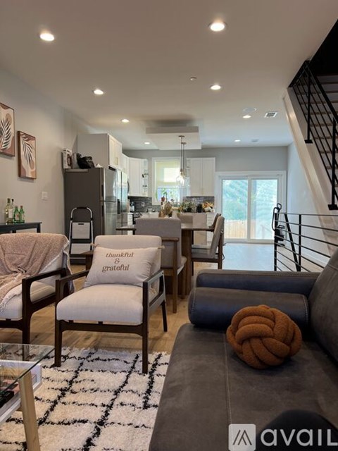 A living room with a couch, chairs, and a rug with the word "AVAIL" on it.