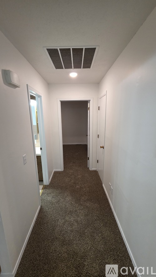 A long hallway with a carpeted floor and white walls.