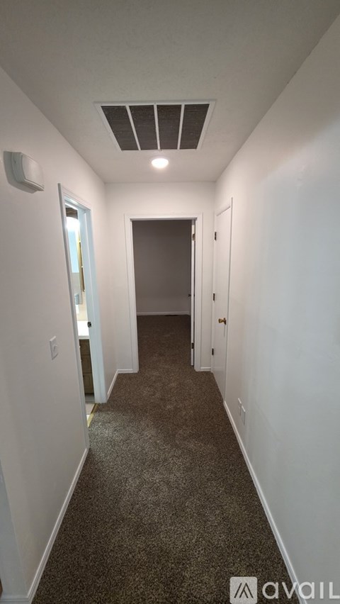 A long hallway with a carpeted floor and white walls.